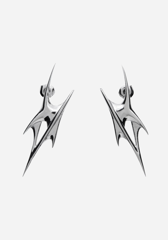 A pair of silver-toned geometric drop earrings with a sharp, angular spike design, shown against a plain light gray background.