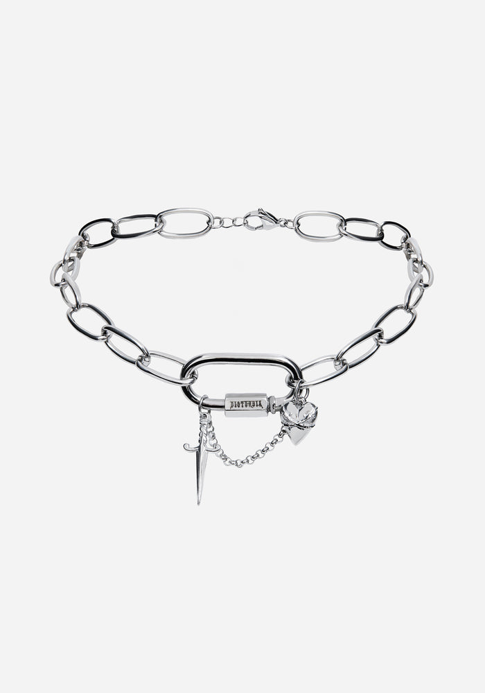 A close-up of a silver chain necklace with a large open rings and dangling cross charms