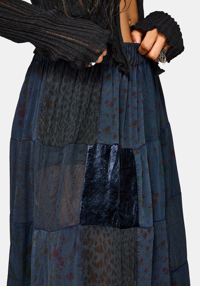 Woman wearing a black top and long navy plaid skirt on a white background