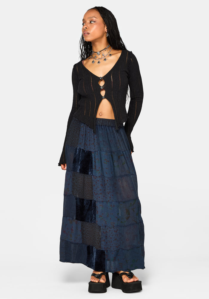 Woman wearing a black cardigan and layered navy maxi skirt on a white background