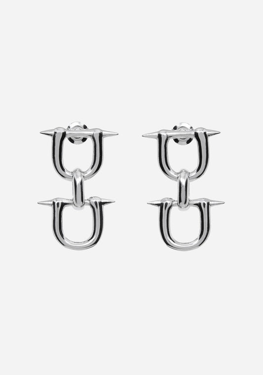 A pair of silver-toned U-shaped hoop earrings with sharp spike details on the front, shown against a plain light gray background.