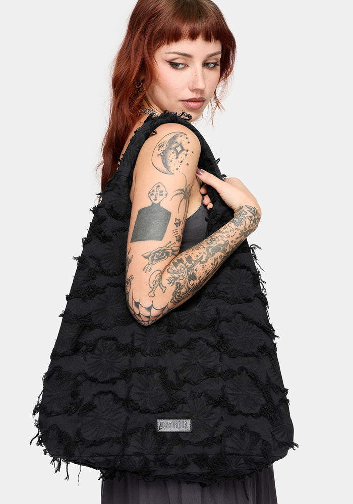 Model holding a black textured shoulder bag