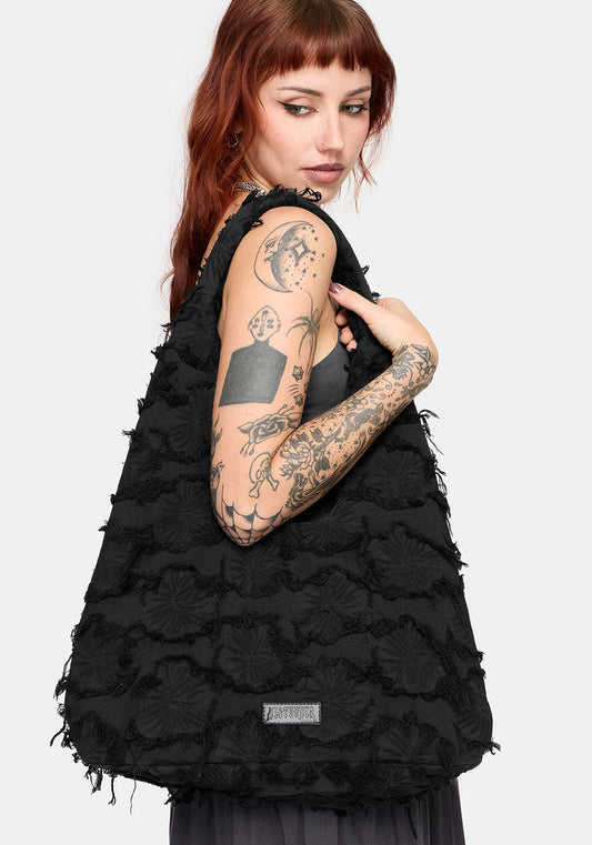 Model holding a black textured shoulder bag